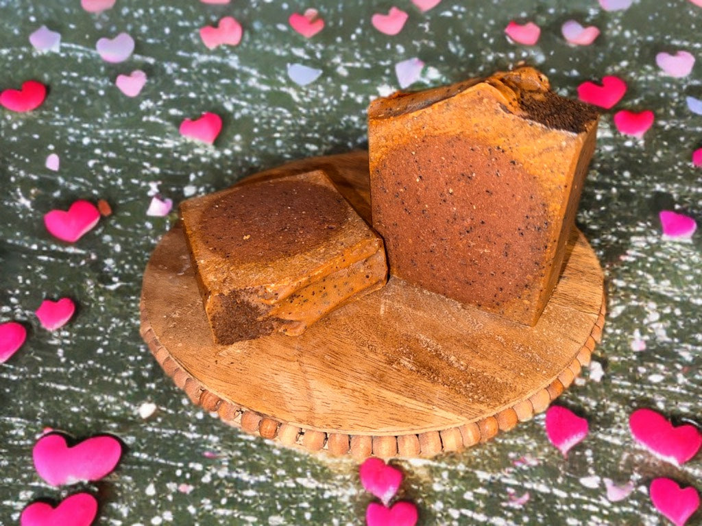 Two pieces of brown soap on a wooden board with heart-shaped confetti on a dark background