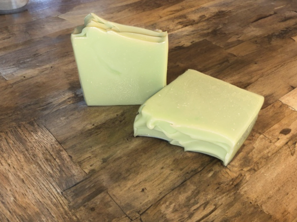 Two light green bars of soap on a wooden surface