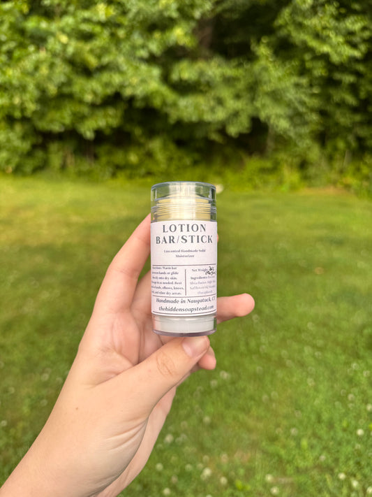 Hand holding a lotion bar stick with a natural background